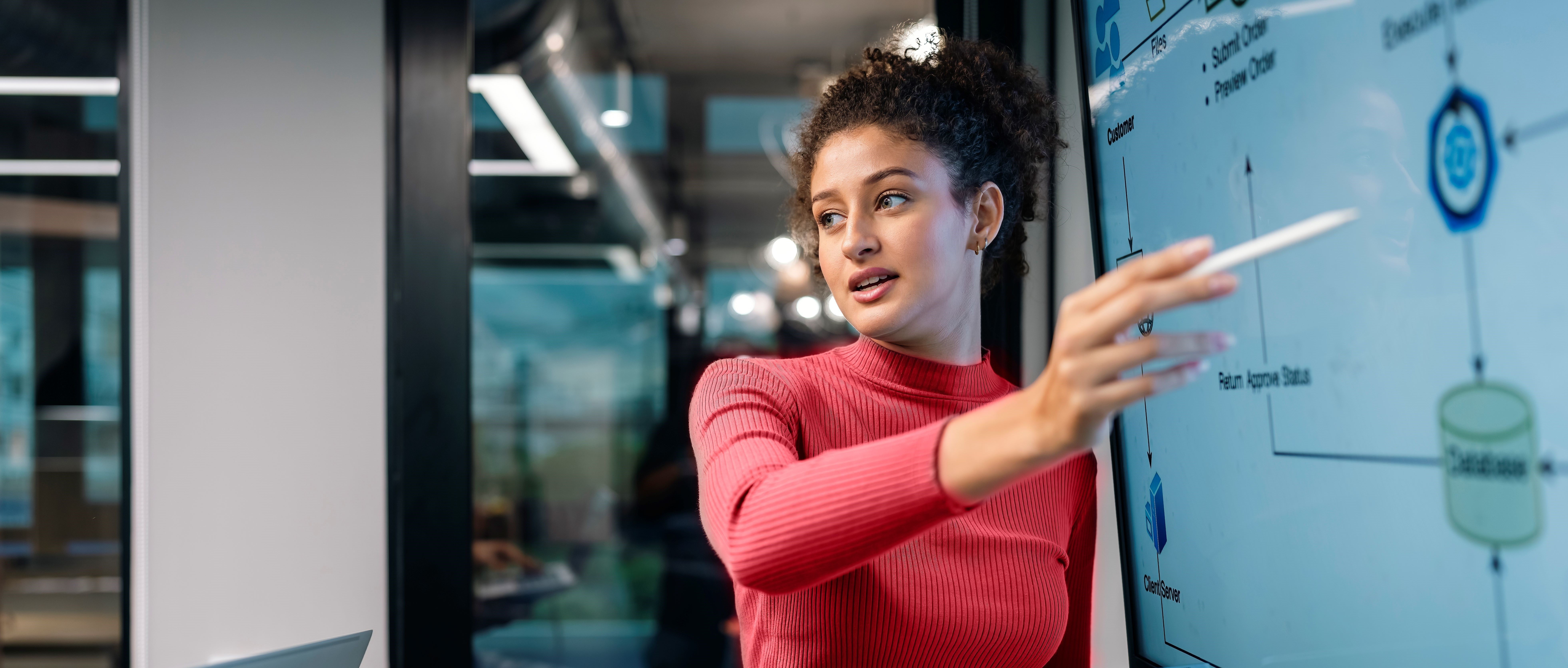 Woman pointing to technical layouts on a white board