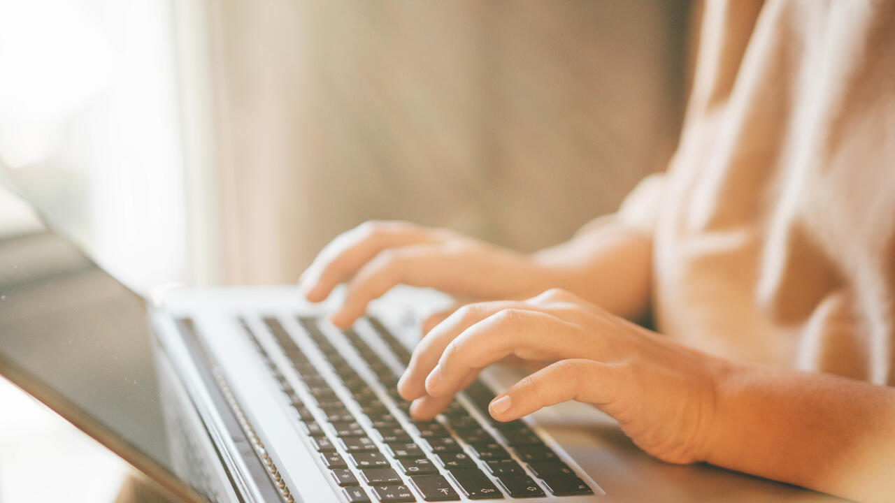 Close up of female hands typing on a laptop keyboard.