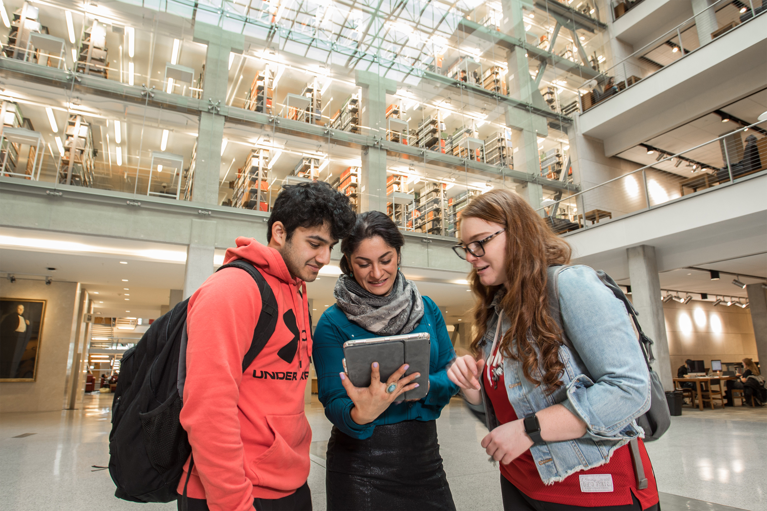 Three students in Thompson Library looking at a tablet