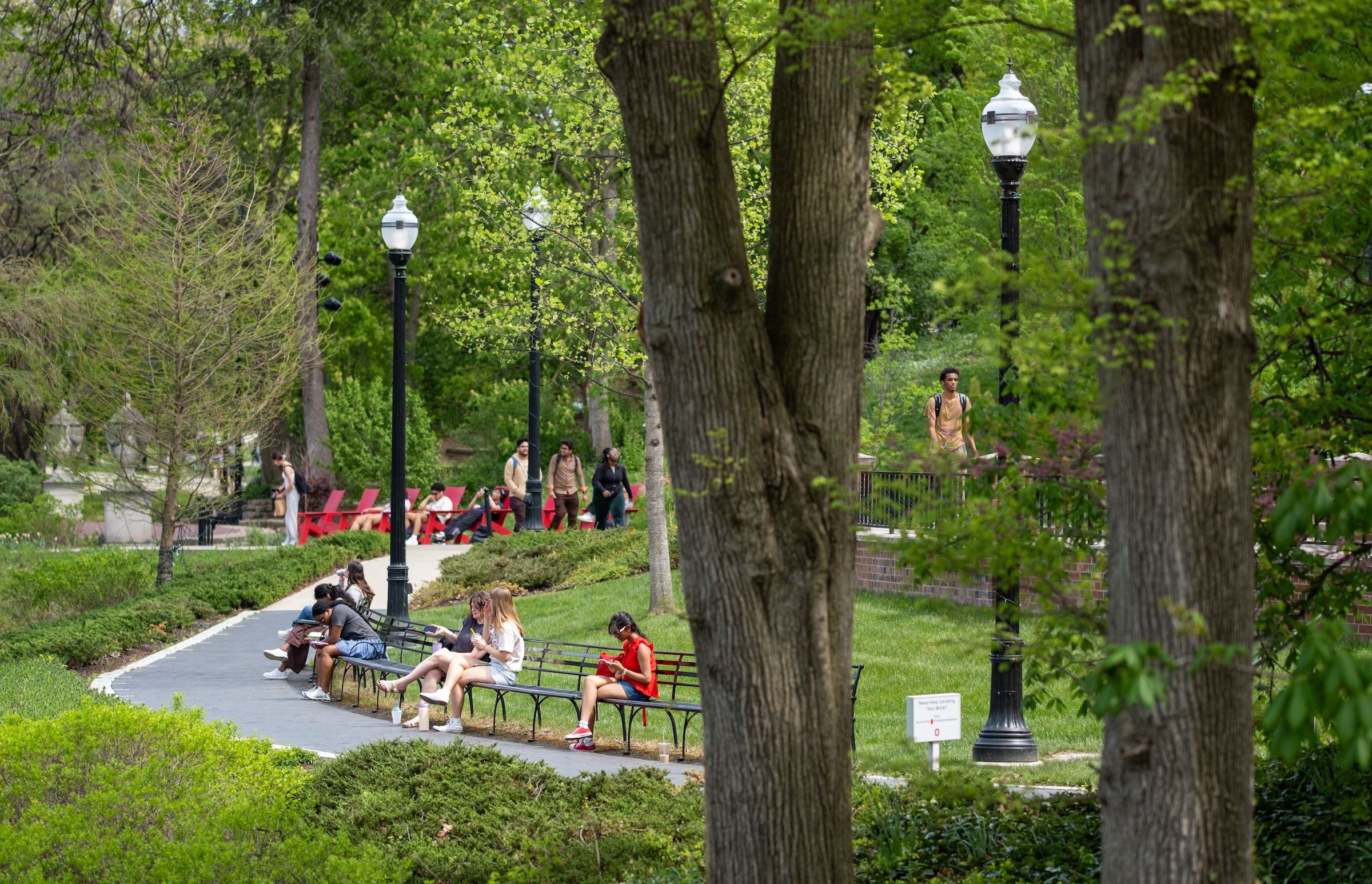 Students seated on benches along a pathway on Ohio State campus.