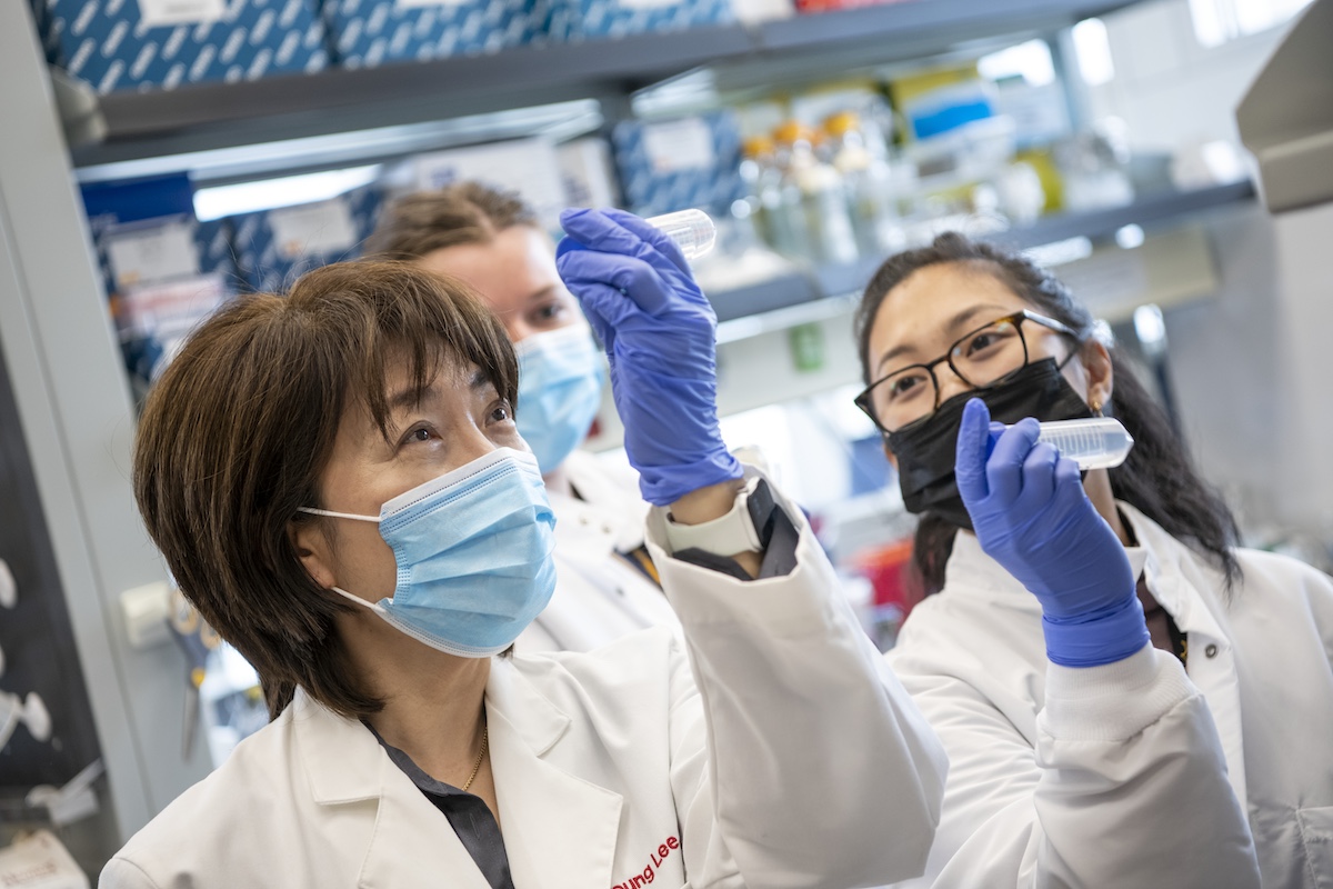 Three lab technicians examine a sample in the lab.