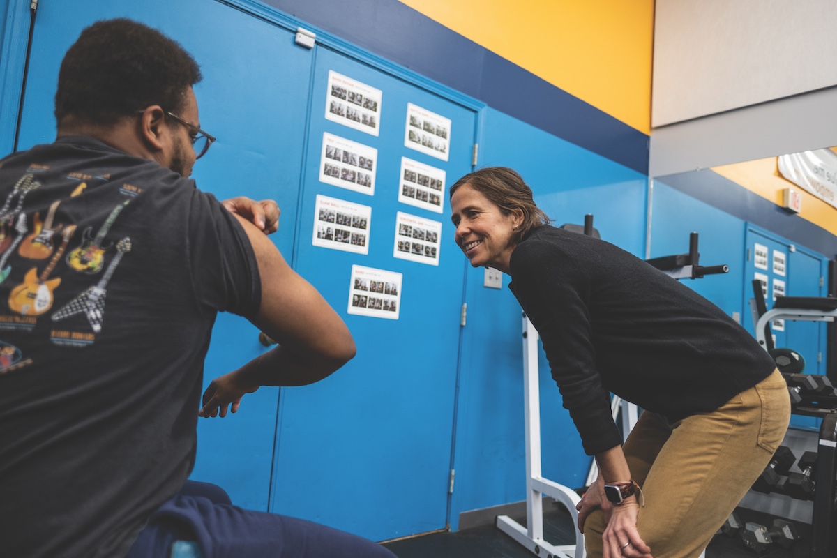 An instructor speaks with a member of the public in the gym.