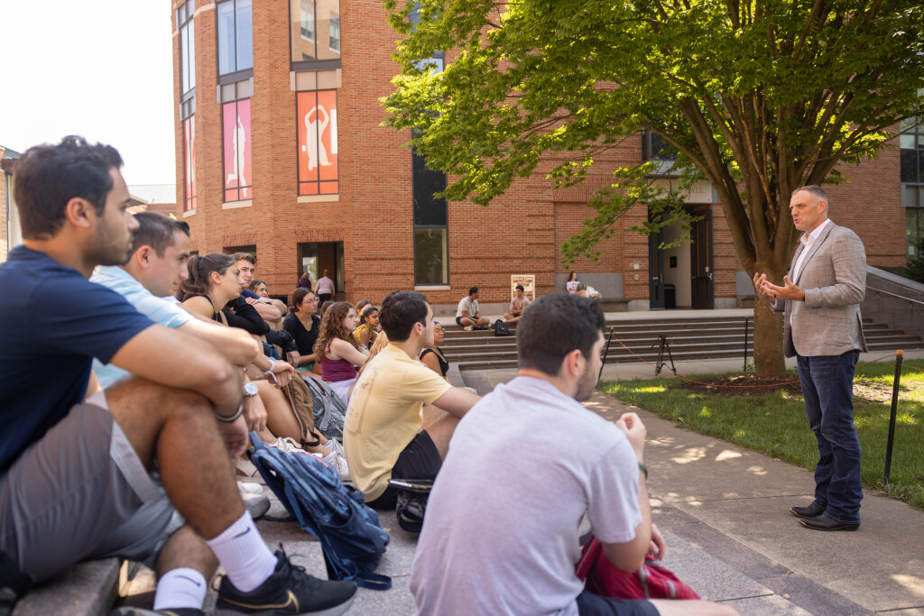 A professor speaks with his class outside on campus.