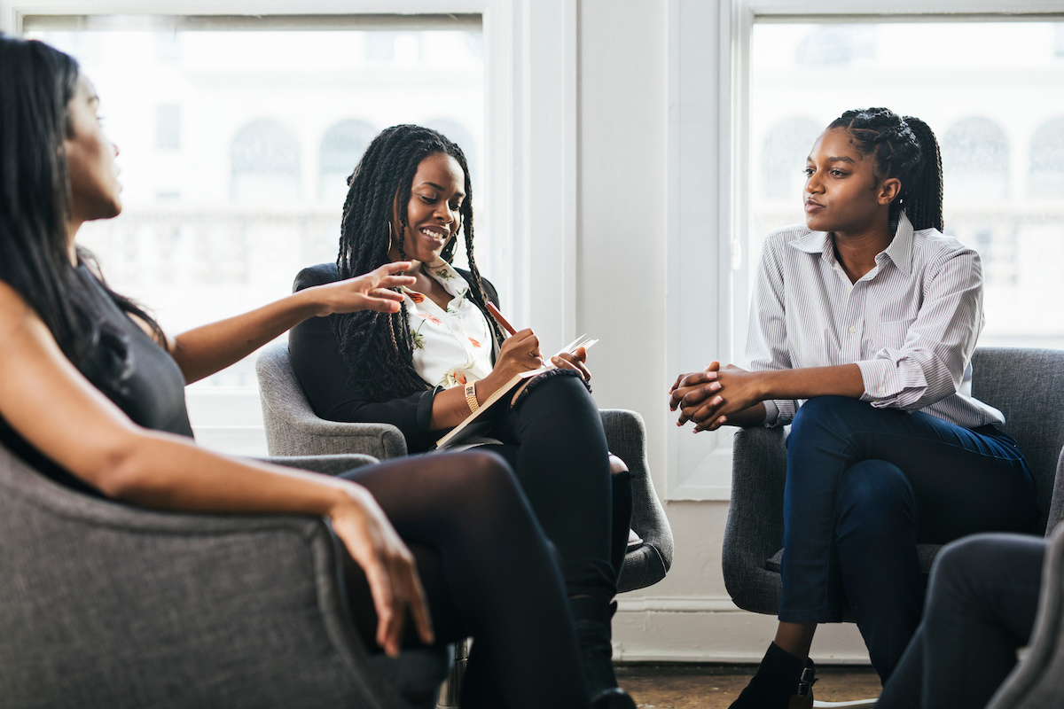 Three women sit and deeply discuss a topic of interest.