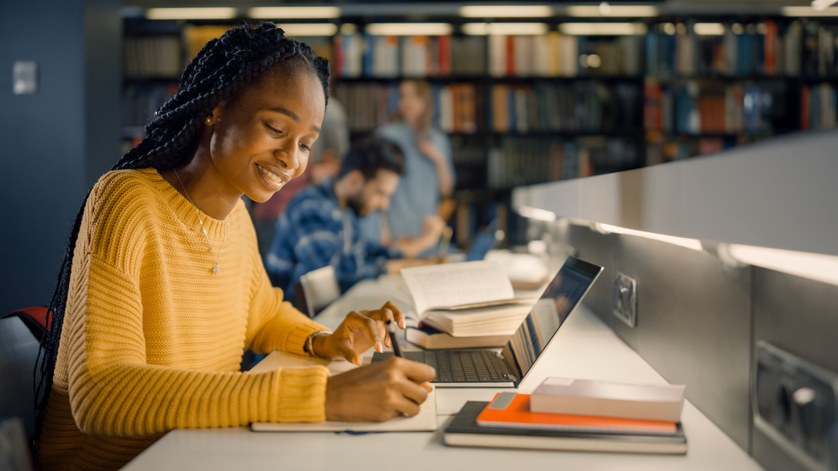 A young woman sits in front of a computer and studies in a library.