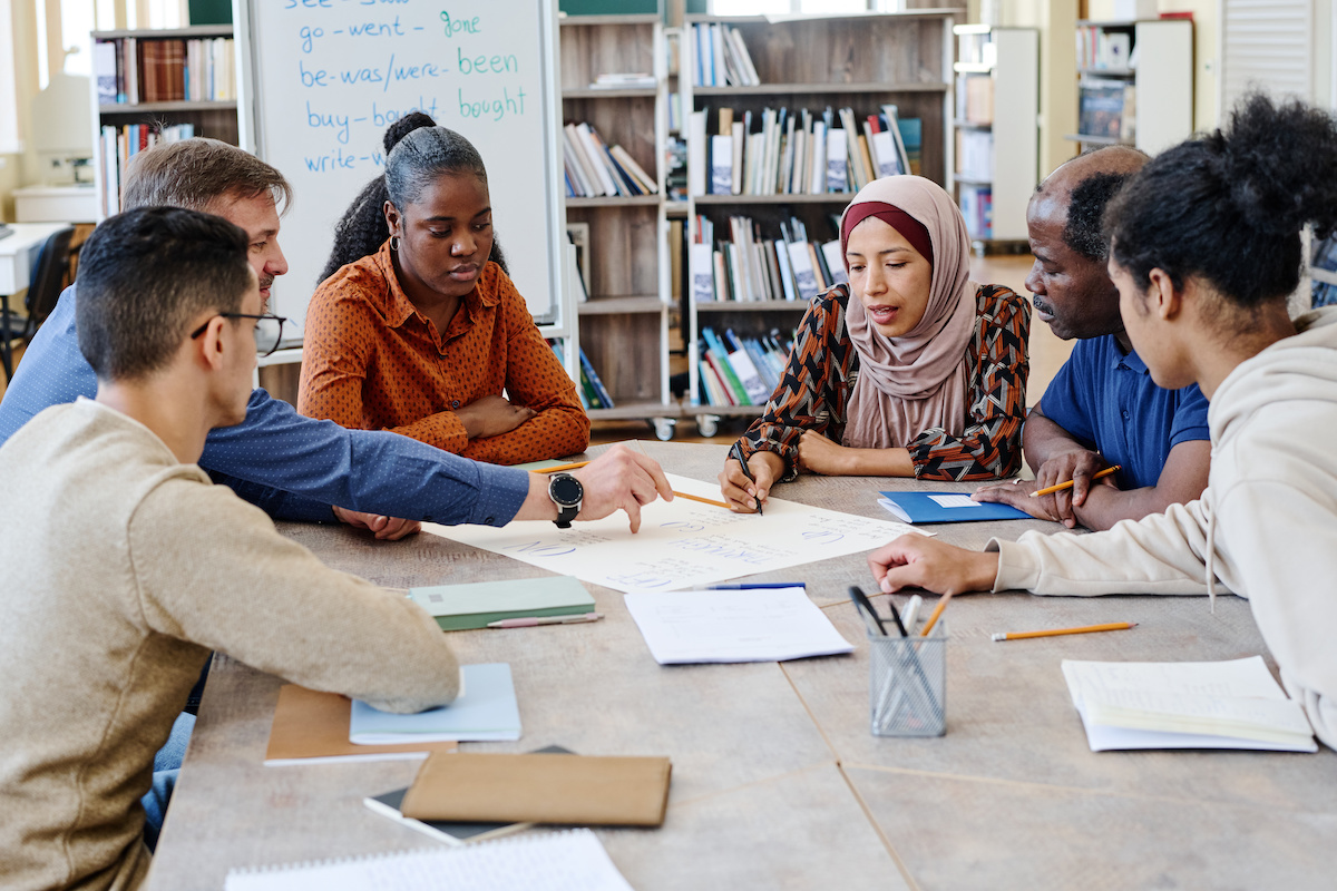 A workgroup sits around a table discussing paper handouts.