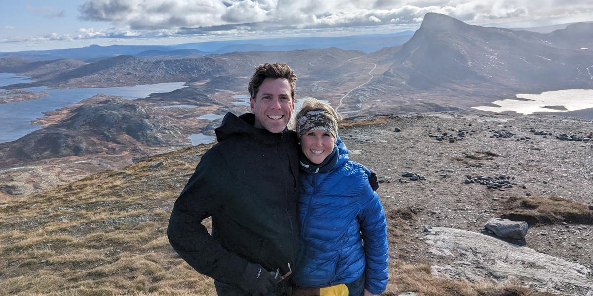 Two people at the top of a mountain range.