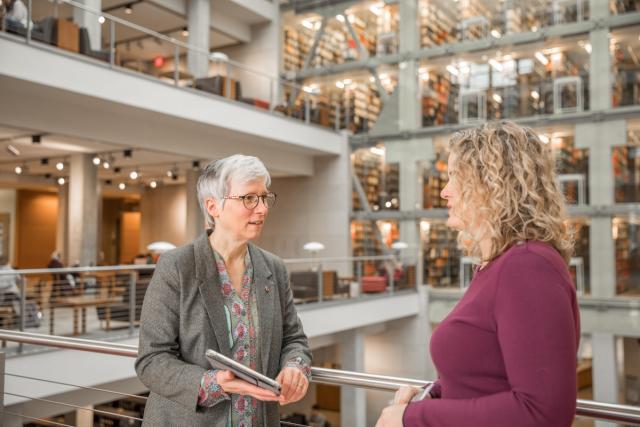 Two women colleagues talk in Thompson Library.