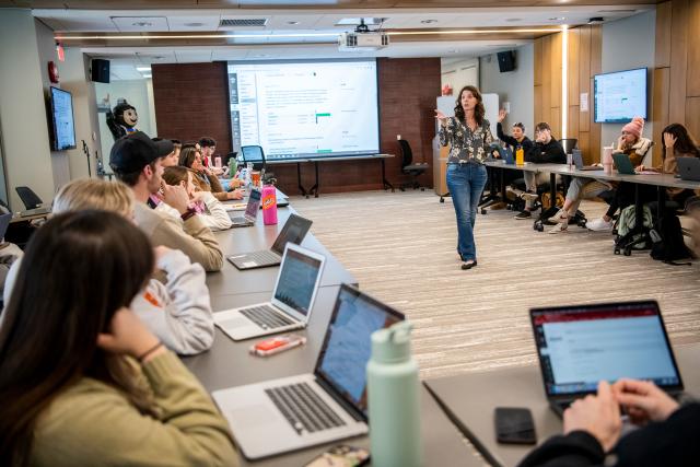 Professor lecturing in front of a classroom with students sitting in the round