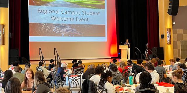 Students at tables viewing a conference slide presentation