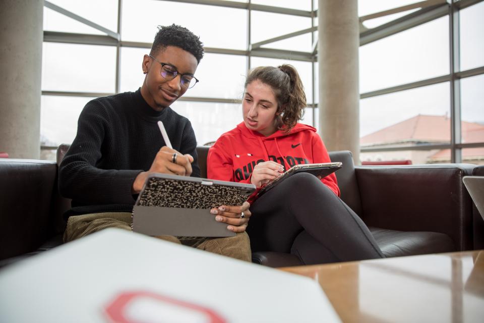 Two students examine a problem on a tablet.