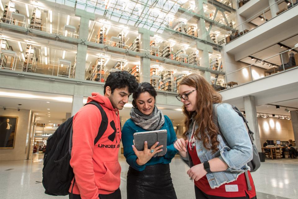 Three students in Thompson Library looking at a tablet