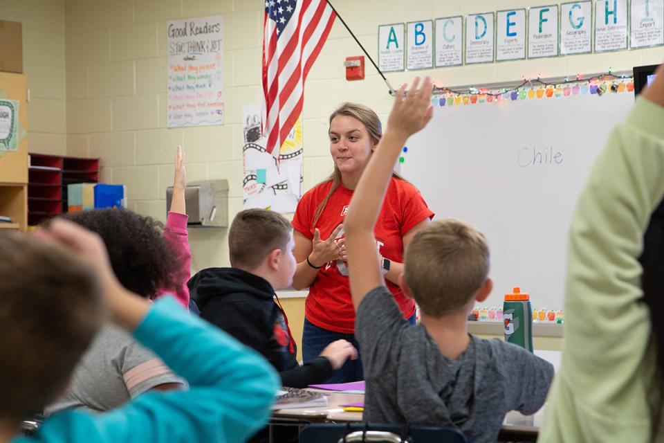 Teacher in classroom with room full of students